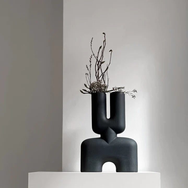 A black 101Cph Cobra Double Medio Black 212006 vase sits on top of a white pedestal.