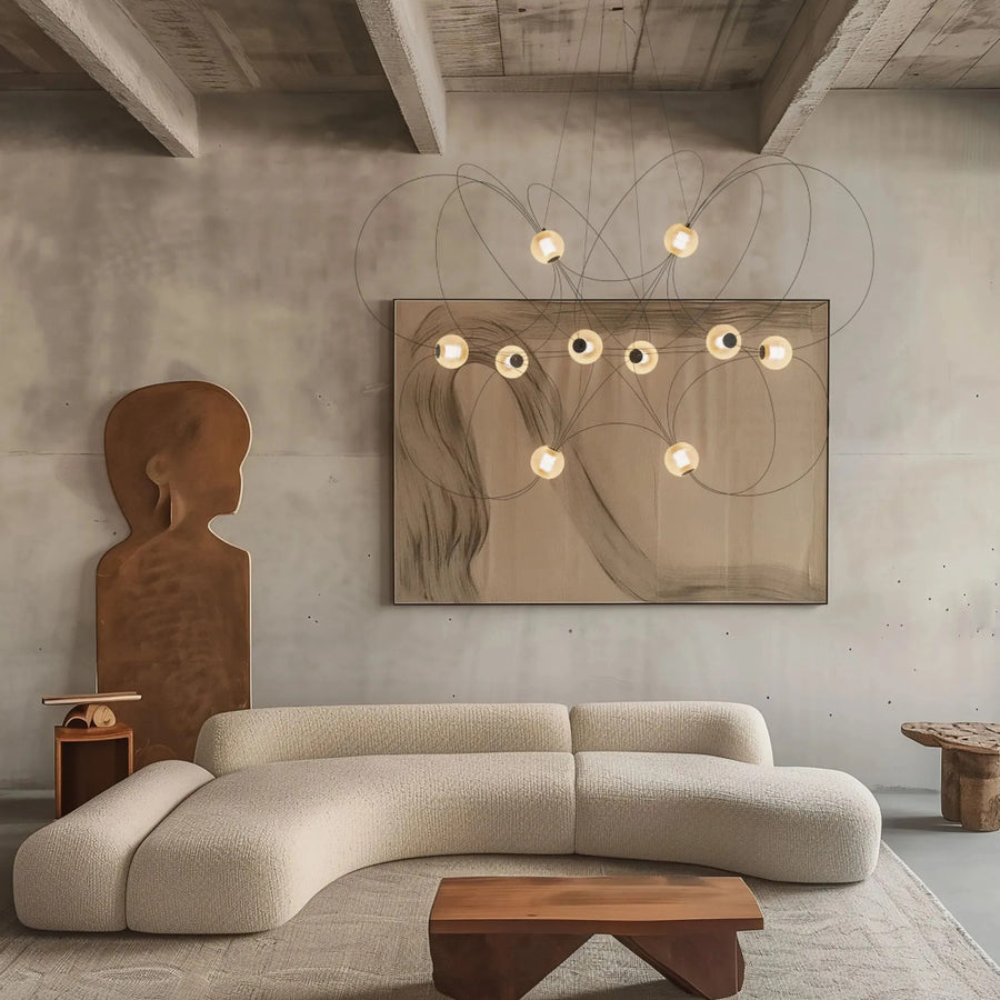 Modern living room with a curved beige sofa, abstract painting, wooden coffee table and a minimalistic chandelier by DCW Editions from Spacio retail store in Mumbai. 