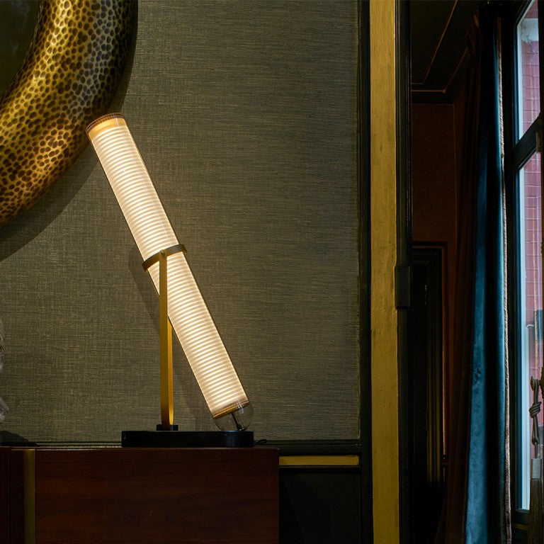 La Lampe Frechin table lamp by DCW Editions in a dark theme interior next to a wall mirror. 