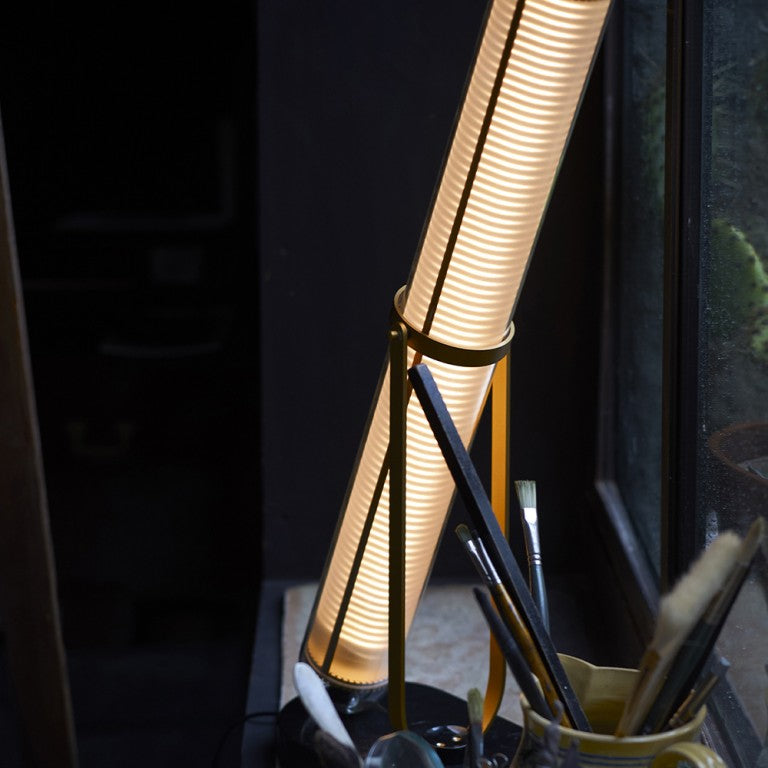 La Lampe Frechin table lamp by DCW Editions  lit up on a window sill. 
