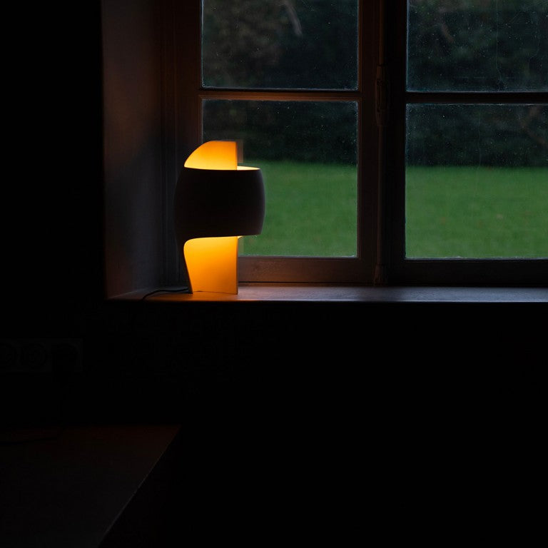 A small lamp from DCW Editions on a windowsill with a dark background