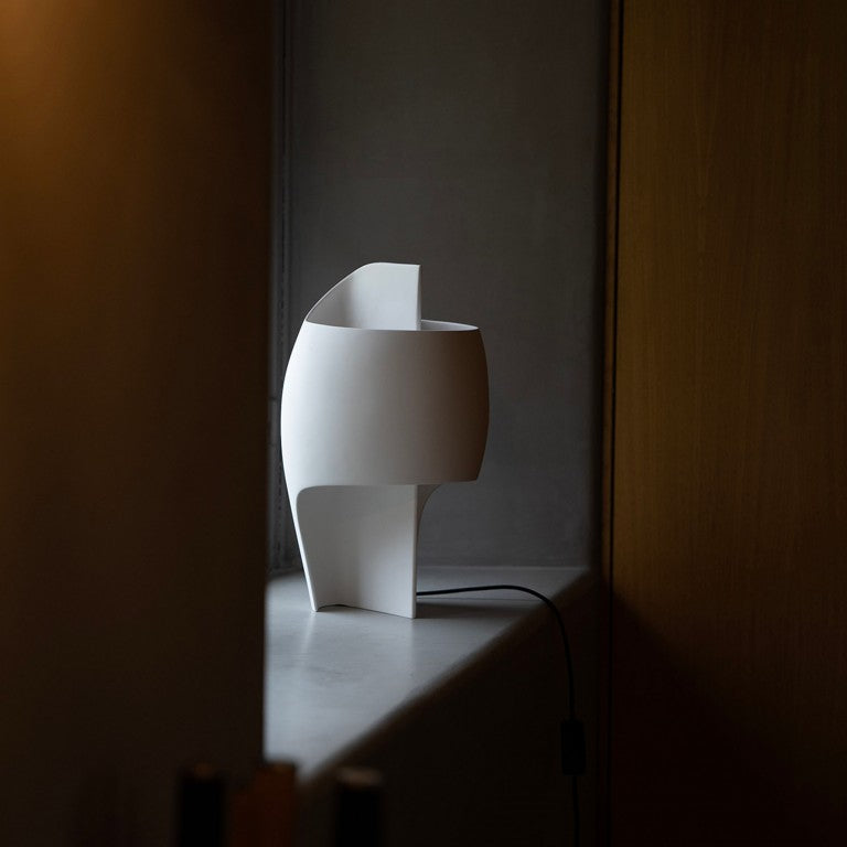 White abstract table lamp on a dark surface with a dark background