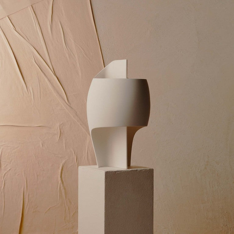 White table lamp on a beige pedestal against a textured beige wall