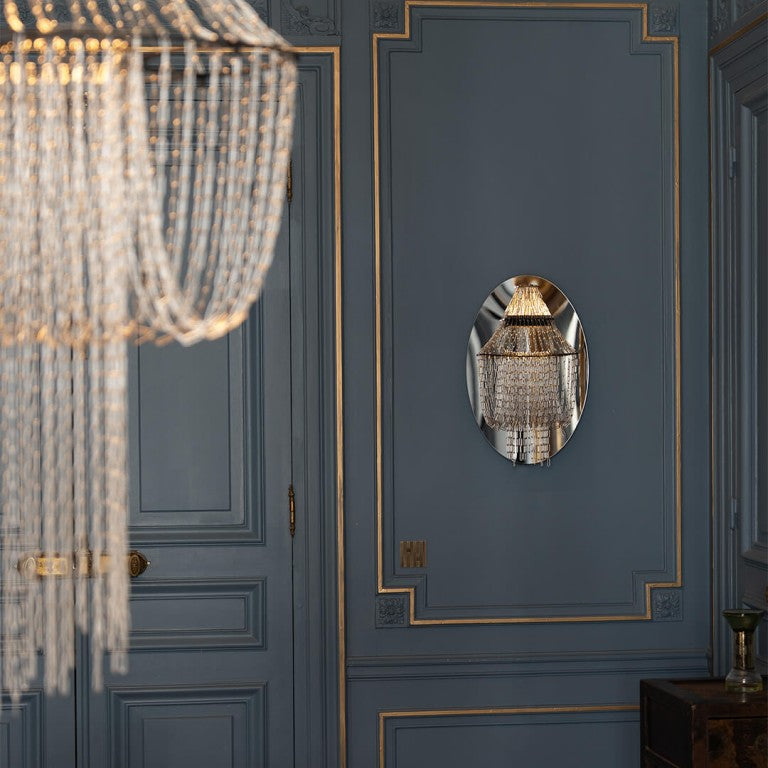 Chandelier and wall mirror reflection on a blue paneled wall