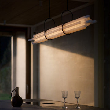 NL12 Suspension chandelier from DCW Edition above a long table styled with water jug and crystal glass