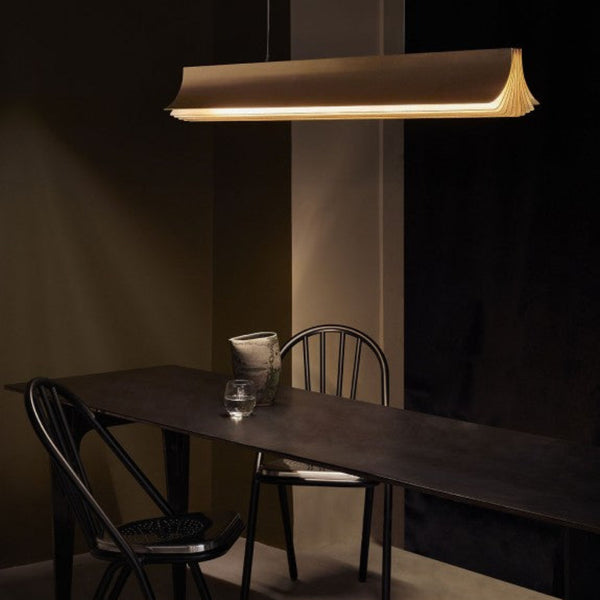 Respiro suspension lamp in brass from DCW Editions above a long black table