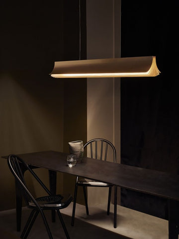 Respiro suspension lamp in brass from DCW Editions above a long black table