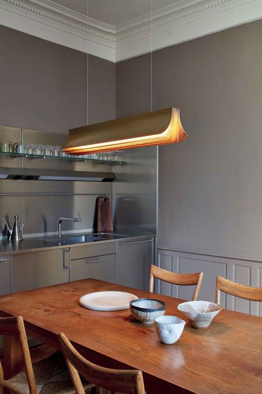 Respiro suspension lamp in brass from DCW Editions above a dining table