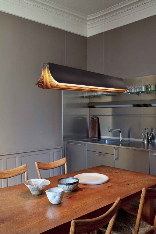 Respiro suspension lamp in brass from DCW Editions above a dining table