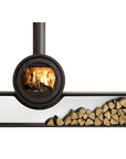 A modern black wood-burning stove with a visible fire inside, shown with a chimney pipe extending upward and a long horizontal shelf holding stacked firewood logs, all on a plain white background.