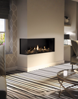 A modern linear gas fireplace with a black firebox and visible flames, set into a beige wall in a styled living room with striped rug, sofa, and glass coffee table.