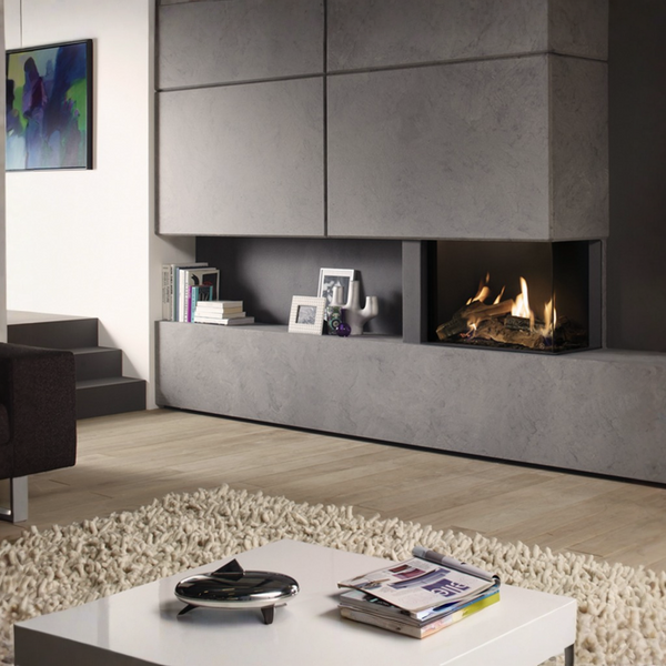 A modern built-in linear gas fireplace with a glowing fire, set into a large gray stone or concrete wall cabinet in a contemporary living room.