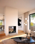 A modern living room interior with a gas fireplace, large windows, a beige sofa, a black round coffee table, and warm natural light streaming in from the outdoors.