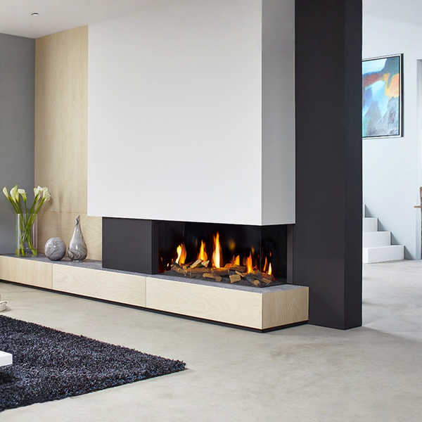 A modern linear gas fireplace with glowing orange flames, set into a low light wood floating mantel in a minimalist contemporary room.