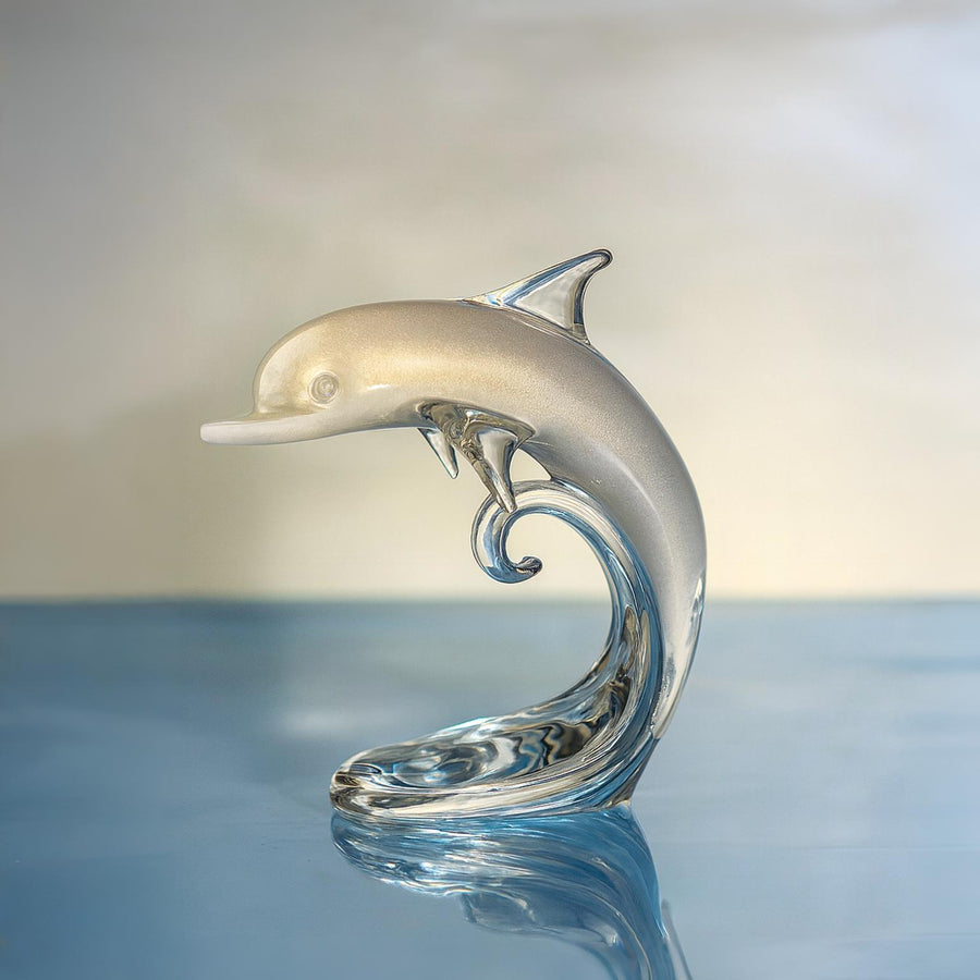 Glass dolphin sculpture on a reflective surface with a blurred background