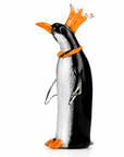 Glass penguin figurine with orange crown on a white background