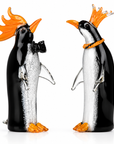 Two glass penguin figurines with orange crowns on a white background