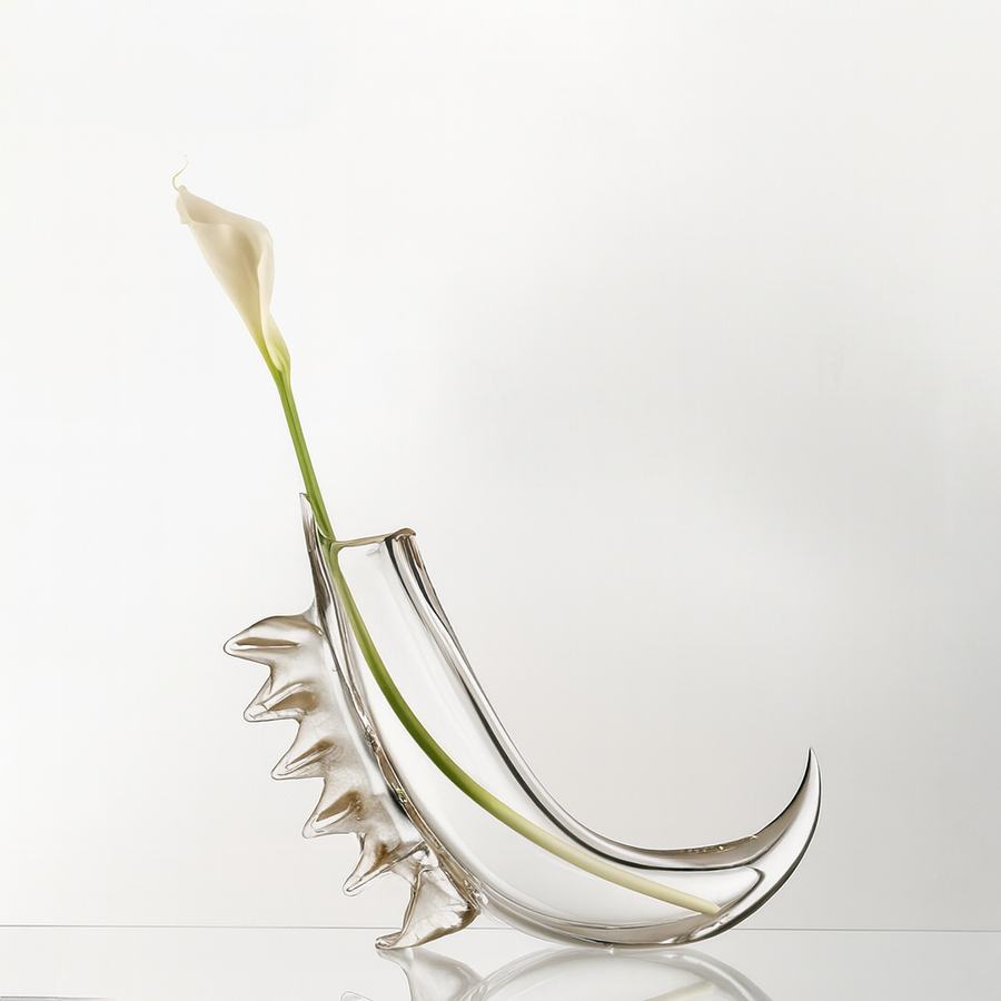 Clear glass vase with a unique design, containing a single white flower on a light gray background.