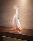 Glass duck sculpture on a wooden surface with a warm background