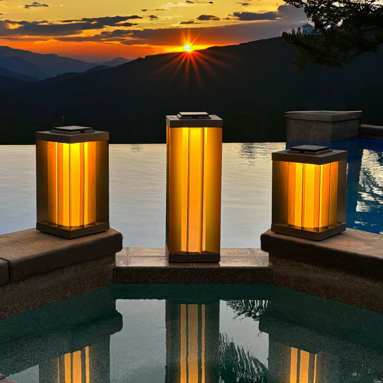 Three solar lanterns by a pool with a sunset over mountains in the background by Les Jardins available at Spacio retail stores in Mumbai & Kolkata. 