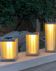 Three illuminated indoor outdoor solar lanterns on a ledge with a garden background by Les Jardins available at Spacio retail stores in Mumbai & Kolkata. 