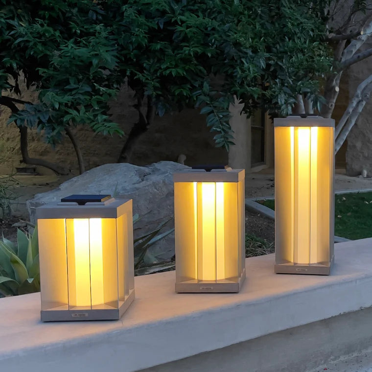 Three illuminated indoor outdoor solar lanterns on a ledge with a garden background by Les Jardins available at Spacio retail stores in Mumbai & Kolkata. 