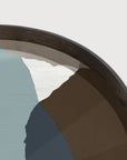 Close-up of a round  wall art cum serving tray with a textured gray background