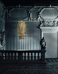 Decorative suspension light hanging in an ornate room with statues and intricate ceiling.