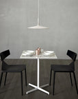 Modern dining setup with a white table and black chairs against a gray wall.