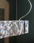 Decorative white ceramic suspension lamp with floral patterns hanging against a dark background
