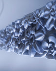 Close-up of a floral-patterned ceramic suspension lamp on a light background