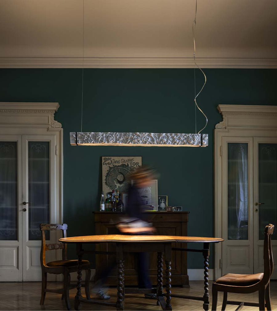 Dining room with wooden table and chairs, dark green walls, and a pendant light.