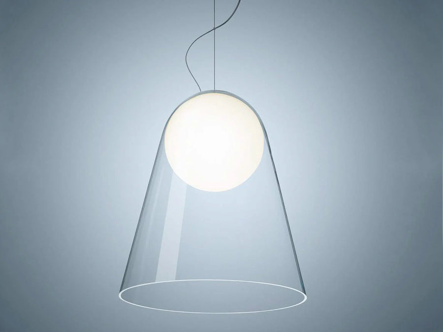 Modern pendant light with a clear glass shade on a gray background