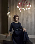 Woman in a dark dress sitting on a bench with modern chandeliers hanging above.