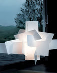 Modern lamp with geometric design in front of a window with a view of trees and mountains.