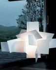 Modern lamp with geometric design in front of a window with a view of trees and mountains.
