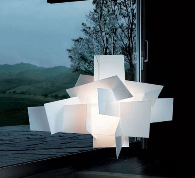 Modern lamp with geometric design in front of a window with a view of trees and mountains.