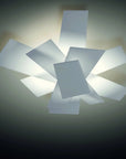 Ceiling light fixture with multiple square glass panels on a plain wall.