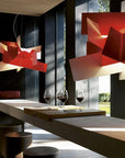 Modern interior with red geometric pendant lights, a table with wine glasses, and a view of greenery outside.
