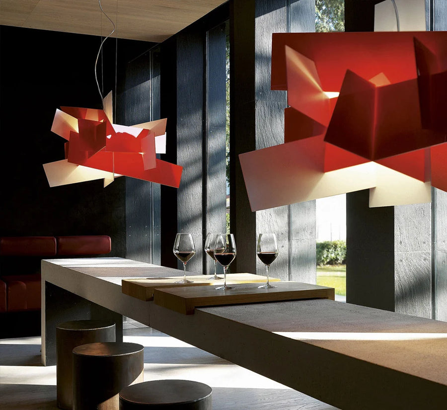 Modern interior with red geometric pendant lights, a table with wine glasses, and a view of greenery outside.