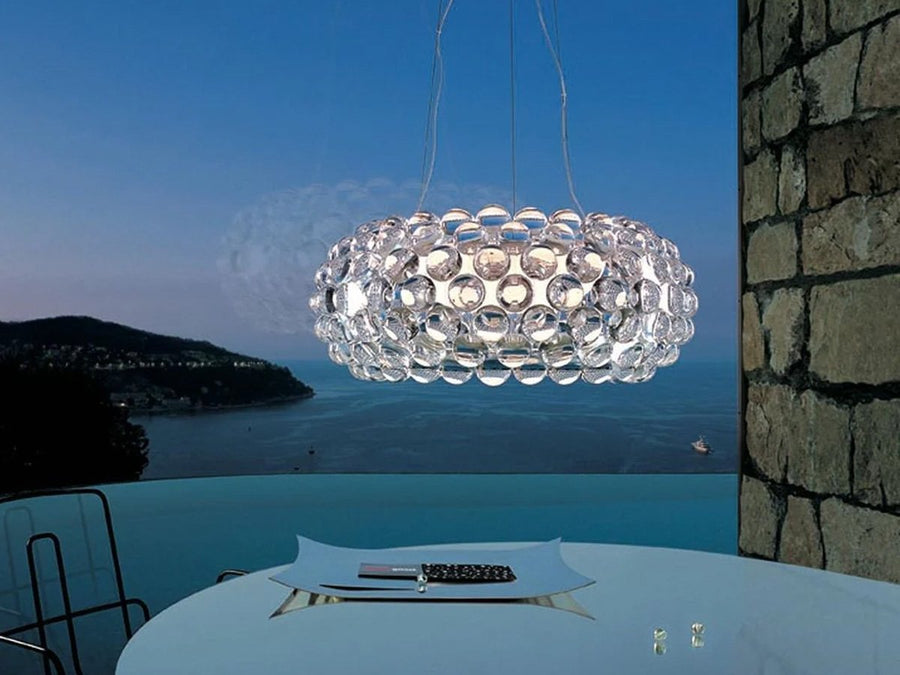 Modern chandelier hanging above a dining table with a scenic background