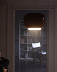 Person sitting in a dimly lit room with a bookshelf in the background