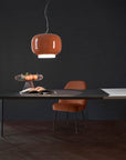 Modern office setup with a desk, chair, and pendant light against a dark wall.