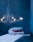 Modern chandelier hanging in a room with blue walls and white furniture.