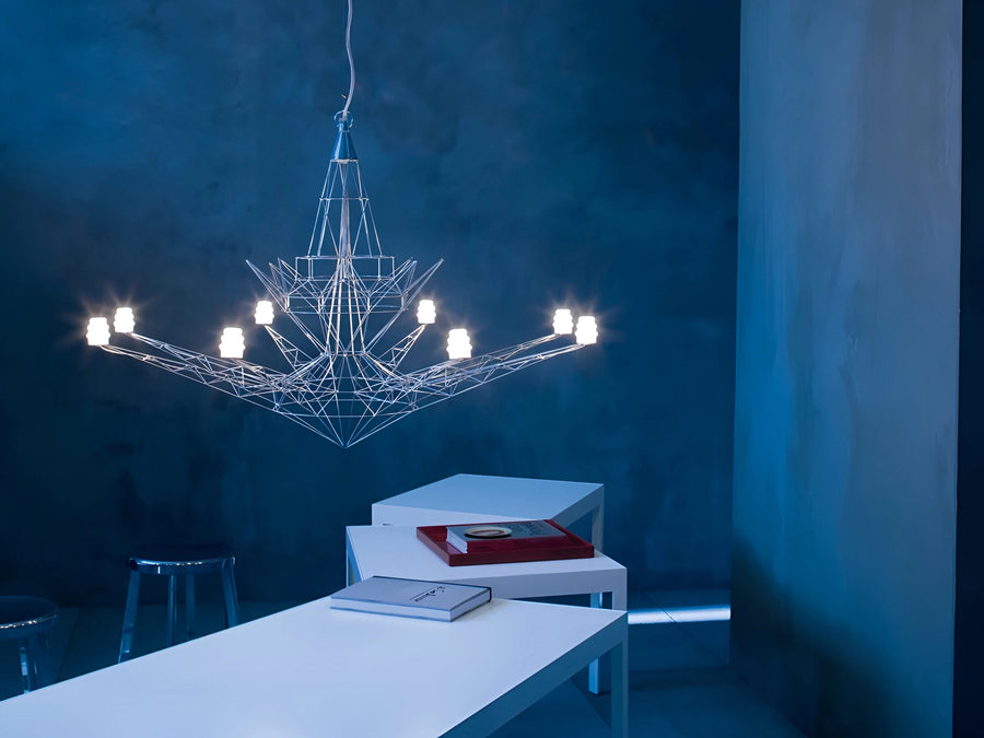 Modern chandelier hanging in a room with blue walls and white furniture.