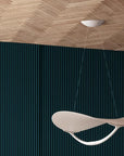 Modern pendant light hanging from a wooden ceiling with a dark blue wall background
