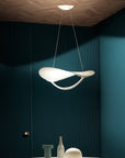 Modern pendant light hanging in a room with dark blue walls and decorative items on a table.