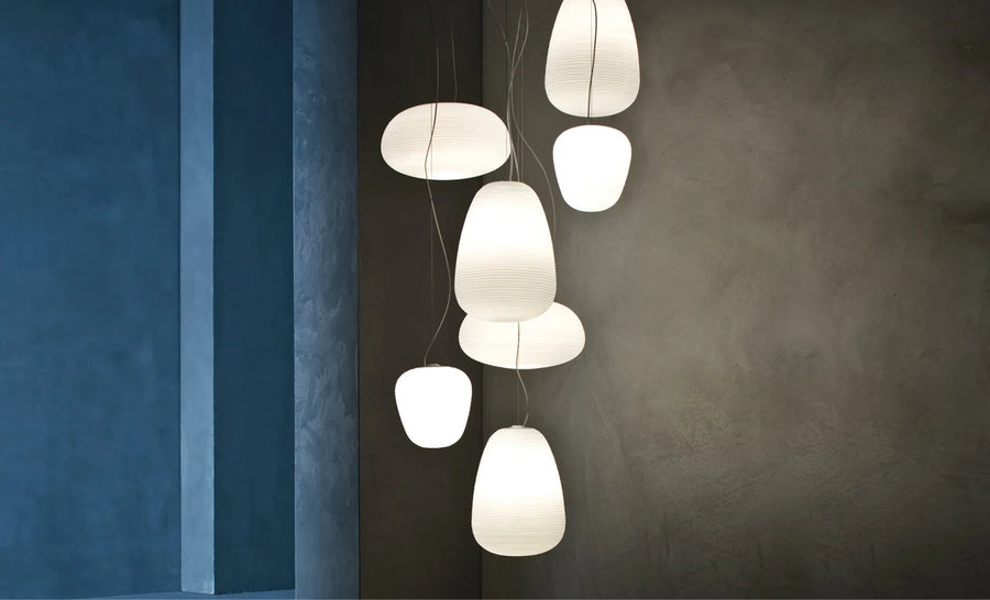 Modern pendant lights hanging against a dark wall with a blue accent.