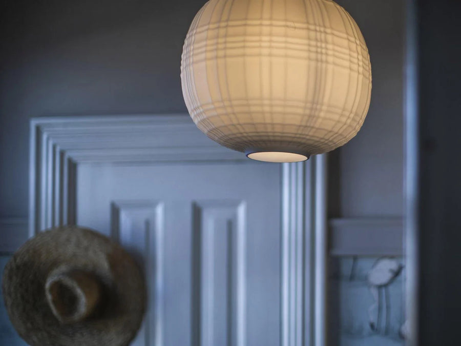 Round woven pendant light hanging against a neutral wall.