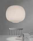 White spherical pendant lamp hanging above a minimalist table and chairs against a gray background